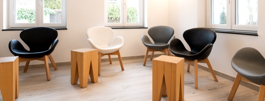Wartezimmer mit Sesseln und Holzhockern